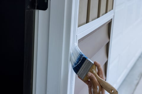 Professional painter using brush to paint wooden moldings and door trims