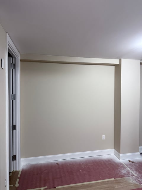 Empty room with beige walls, white trim, red carpet, closet door on left, and white outlet on wall