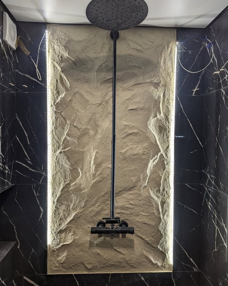 Modern shower enclosure with black marble walls, cream textured back panel, and rainfall showerhead mounted on black pipe