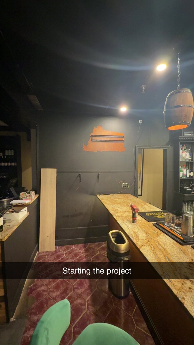 Interior of garage or workshop being renovated, with work bench, orange heating lamp, and dark walls under construction