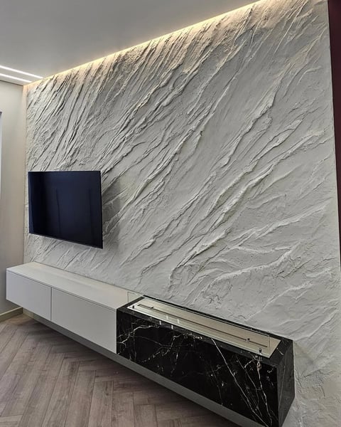Modern living room with wall-mounted TV on white marble accent wall above a white and black marble media console unit