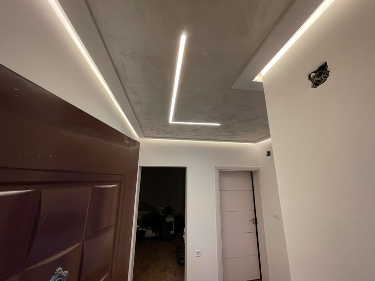 Modern hallway with white walls, brown wooden door, and geometric neon light strips on the ceiling